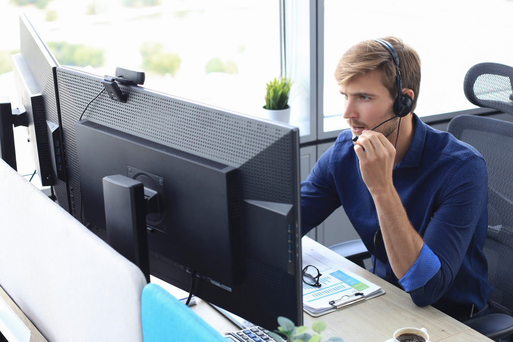An expert IT telemarketing agent sat at a desk speaking intently with a lead.